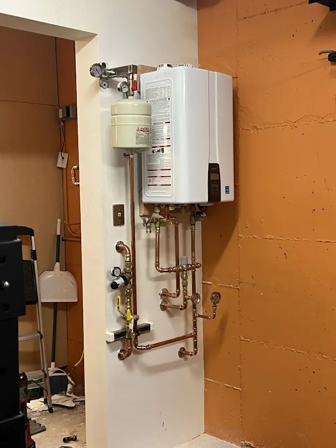 Plumbing technician inspecting water heater connections in Johnston